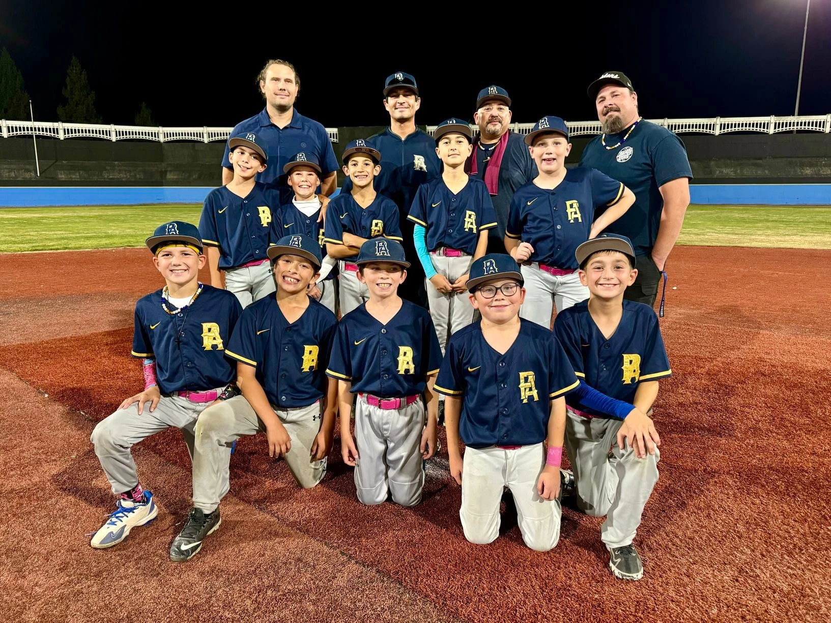 PA players and coaches together on the baseball field in navy uniforms